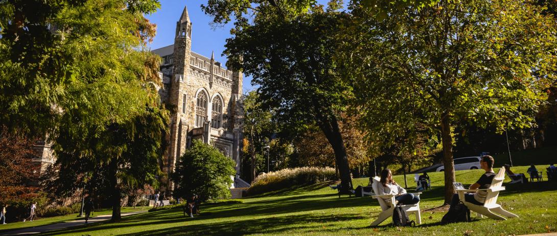 Students sit in adirondack chair in front of the Lehigh University library